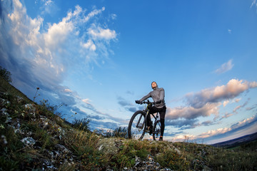 Fototapeta premium Young man cycling on a rural road through meadow