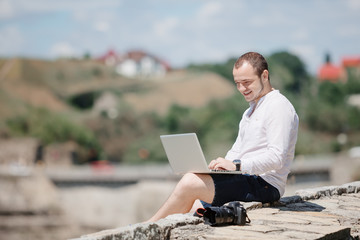 Smiling man using his laptop outside