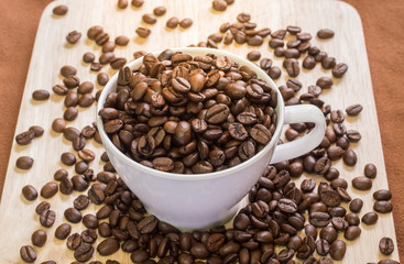 Coffee Cup with coffee beans on wood of coffee beans background.