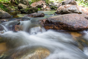 Waterfall cascades flowing over flat rocks in forest.