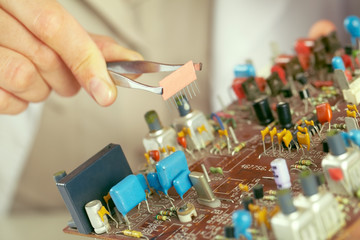 Close-up of human hand holding tweezers and working with computer chip