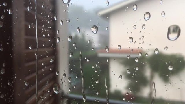 Real rain drops sliding on window glass