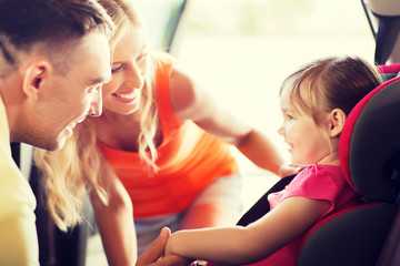 parents talking to little girl in baby car seat