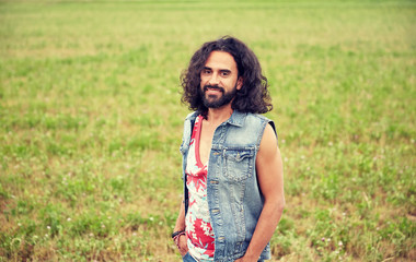 smiling young hippie man on green field