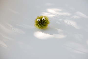 nachdenklich, grüne stachelige Figur mit Zuckeraugen schaut nachdenklich