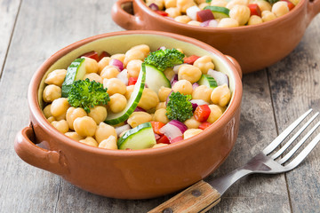 Chickpea salad in bowl on wooden background

