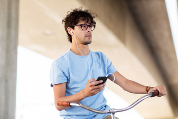 man with smartphone and earphones on bicycle