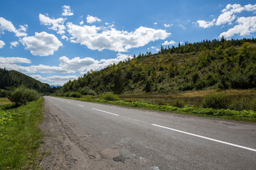 Empty road and mountains on background of the cloudy sky