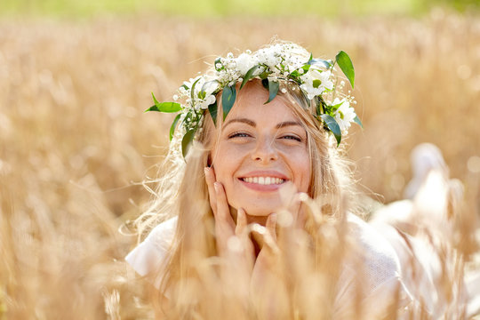 happy woman in wreath of flowers on cereal field