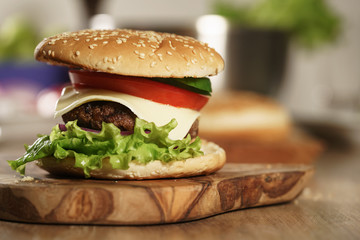 fun made fresh burger with marble beef, cheese and vegetables on olive board