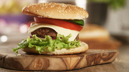 fun made fresh burger with marble beef, cheese and vegetables on olive board