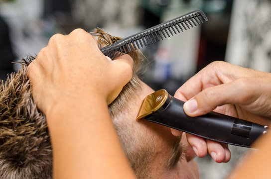Barber cutting and modeling hair by electric trimmer