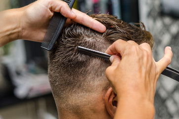 Hairdresser cutting man's hair with toothed razor