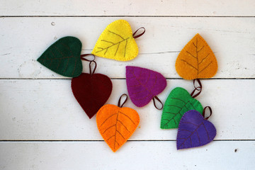 Multicolored autumn leaves from textile fabric on white wooden background