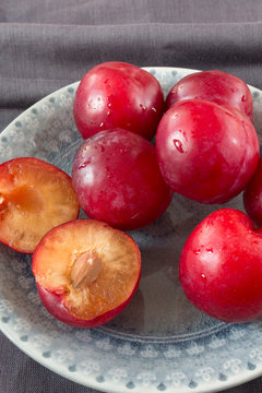 Red plums on grey plate closeup indoor