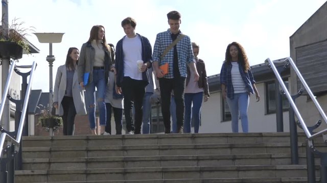 Group of Students walking down steps in a city. They are wearing casual clothing and smiling.
