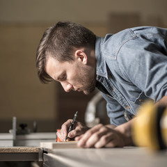 Young carpenter marking cuts