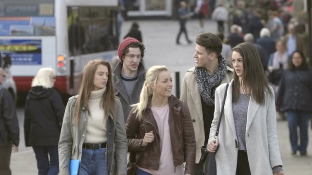 Group of Students walking through the city. They are wearing casual clothing and smiling.