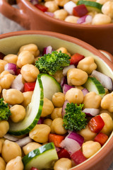 Chickpea salad in brown bowl on wooden background

