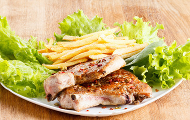 Juicy roasted pork steak with french fries and spices