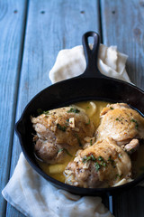Chicken things simmered in a cast iron pan , weathered wood table 
