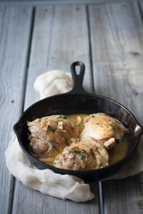 Chicken things simmered in a cast iron pan , weathered wood table 