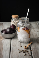 Fototapeta premium A clear glass pitcher filled with ice cubes and sliced plums. Ice the preparation 
