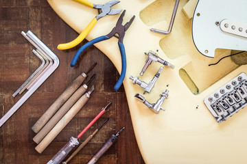 Obraz premium yellow electric guitar on wood in repair & luthier workshop, fixing & musical instrument repairing concept