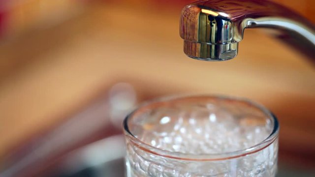 Filling up a glass of fresh water from a kitchen tap