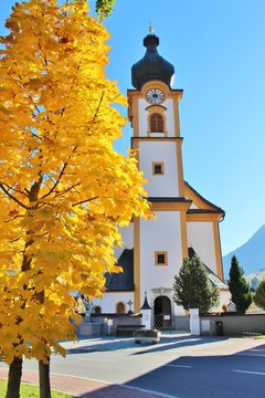 Tree with very yellow autumn leafs and the baroque parish church or Pfarrkirche of Mittersill, Austria. In the Pinzgau, Land Salzburg.