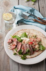 Grilled flat bread with sliced steak, couscous, almonds, spinach, tomatoes and feta cheese 