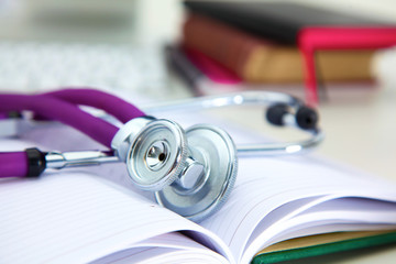 Stethoscope lying on a table an open book