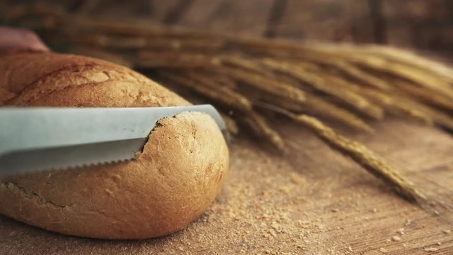Hand cutting loaf of bread with knife, Cutting bread - Close-up, Slice of bread falls on the wooden board, Slice of bread - Close-up. 4 Full HD shots.