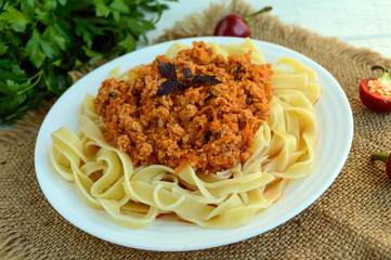 Pasta tagliatelle with meat sauce bolognese on a white plate. The traditional view of food.