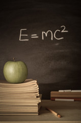 Teacher's Desk with Books, Apple and Theory on Chalkboard