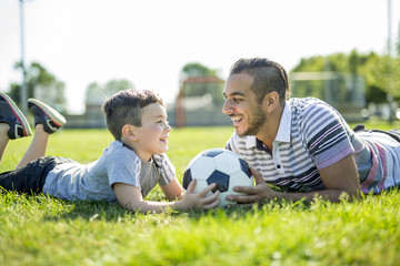 man with child playing football on field