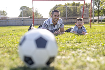 Naklejka premium man with child playing football on field
