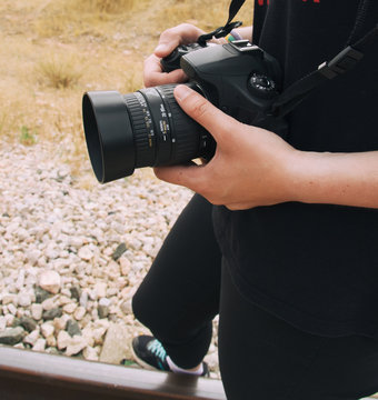 Persona sujetando con las manos su c&aacute;mara r&eacute;flex en una sesi&oacute;n de fotos 