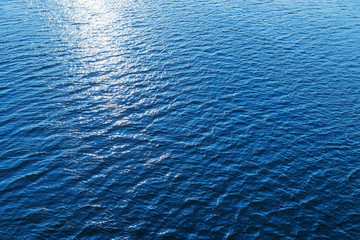 aerial view to blue water with sun reflections