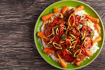 takeawy classic pork on rice with fried in sticky souce carrots, sprinkle of chillie and spring onion.
