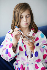 Portrait of moody young girl eating porrige at morning