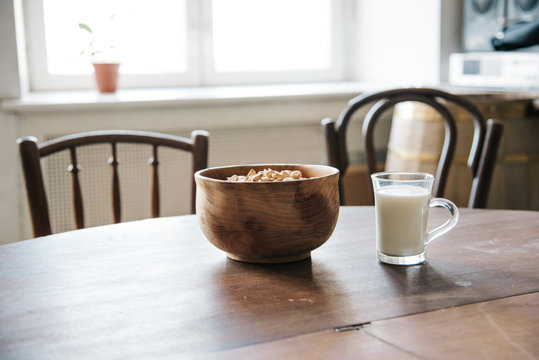 Wooden bowl and cup of milk with crackers on the table.