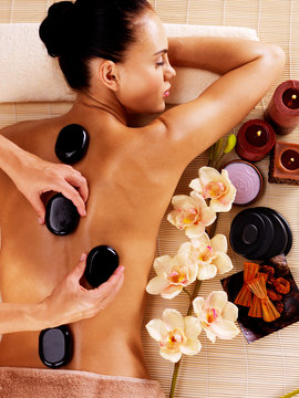 Adult woman having hot stone massage in spa salon