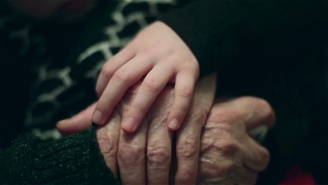 Hand of a little girl fondling old  hands of grandmother with love.