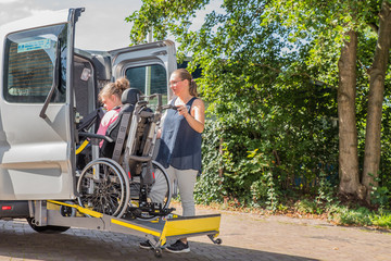 Working together with disability / Disability a disabled child in a wheelchair being cared for by a voluntary care worker