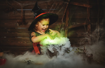 Obraz premium Halloween. child girl witch preparing potion in cauldron