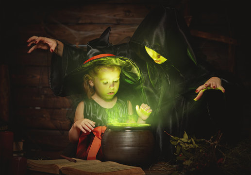Halloween. two witches old and young preparing  potion in cauldr