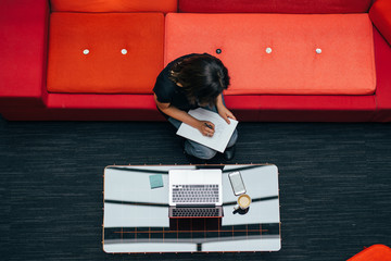 Woman at red sofa with laptop, high angle view 
