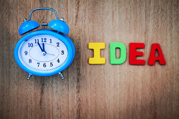 clock and idea word writen on wooden background