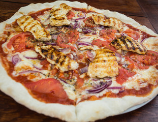 Homemade pizza with chicken on wooden background.